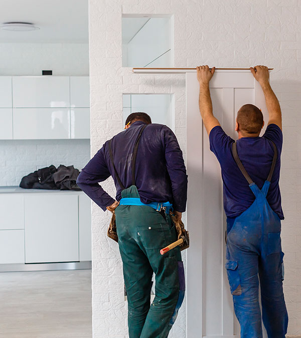 Two men working on an interior door installation