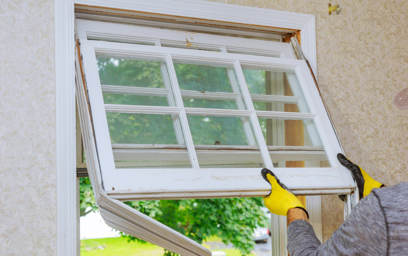 Energy-efficient window installation process: a worker removes the old window